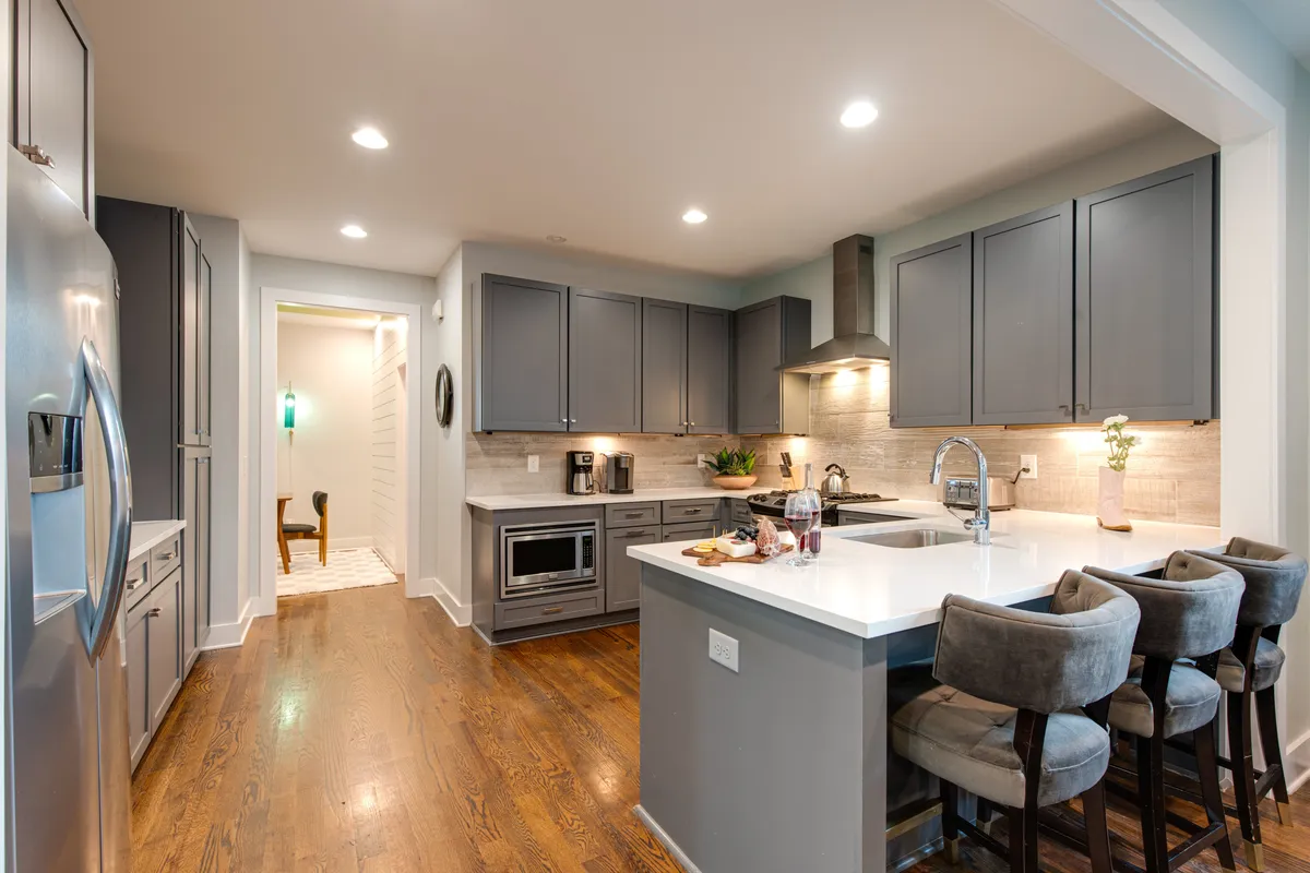 A modern, fully equipped kitchen featuring a central island with bar stools, stainless steel appliances, and open sightlines to the rest of the floor. The space is ready for cooking, casual breakfasts, or entertaining guests around the island.