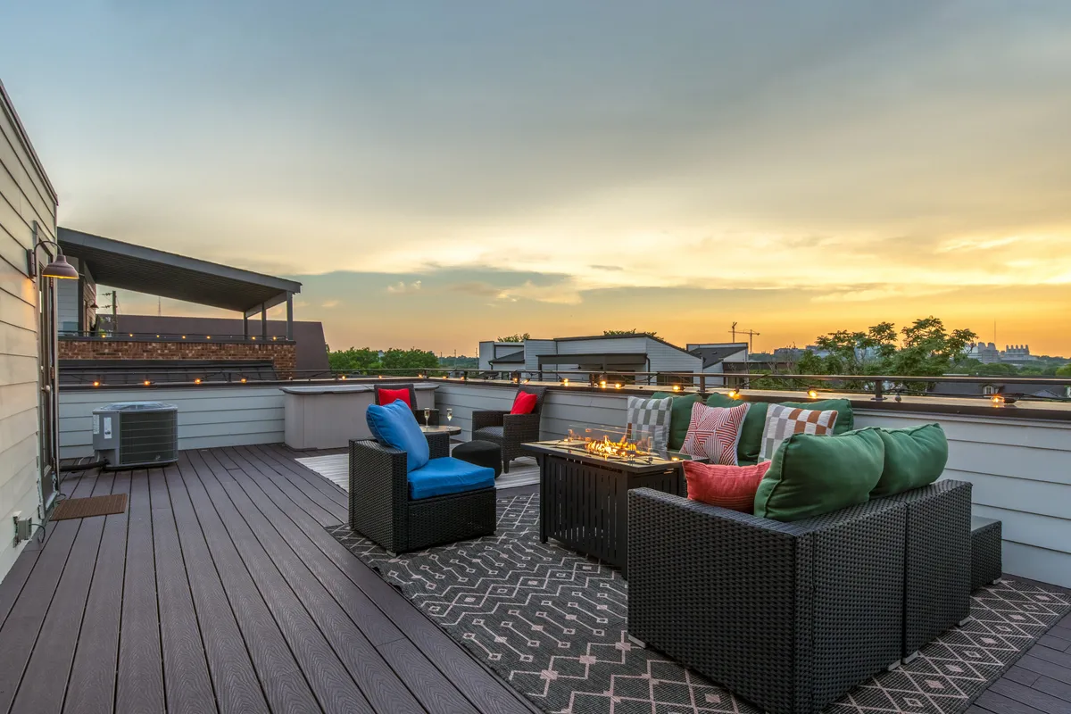 This rooftop deck features cozy outdoor seating, a fire pit, and a sweeping sunset view of the Nashville skyline. The setup is perfect for socializing, relaxing after a night out, and taking group selfies with the city as a backdrop.